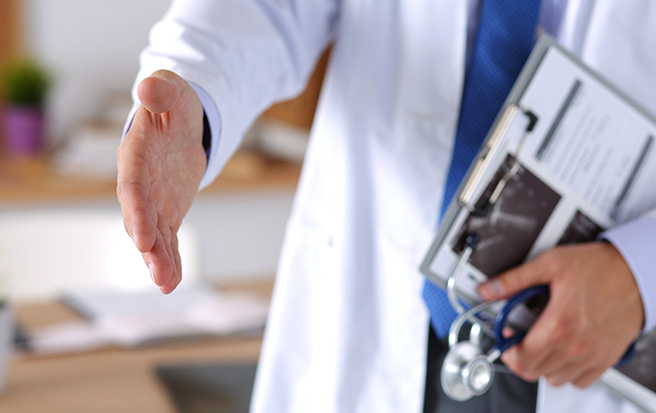 physician with clipboard reaching out his hand to shake